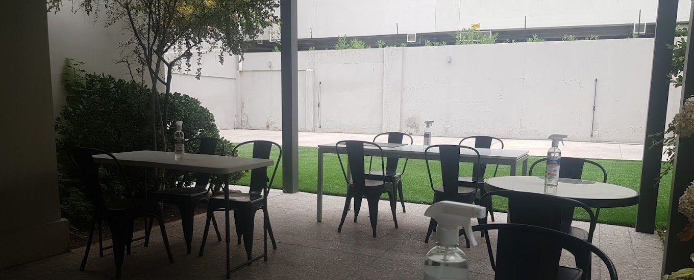 Patio de espera de la notaría, con mesas, sillas y jardín